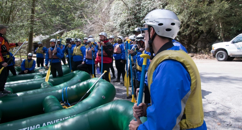 a group of people stand around empty rafts on an outward bound expedition 